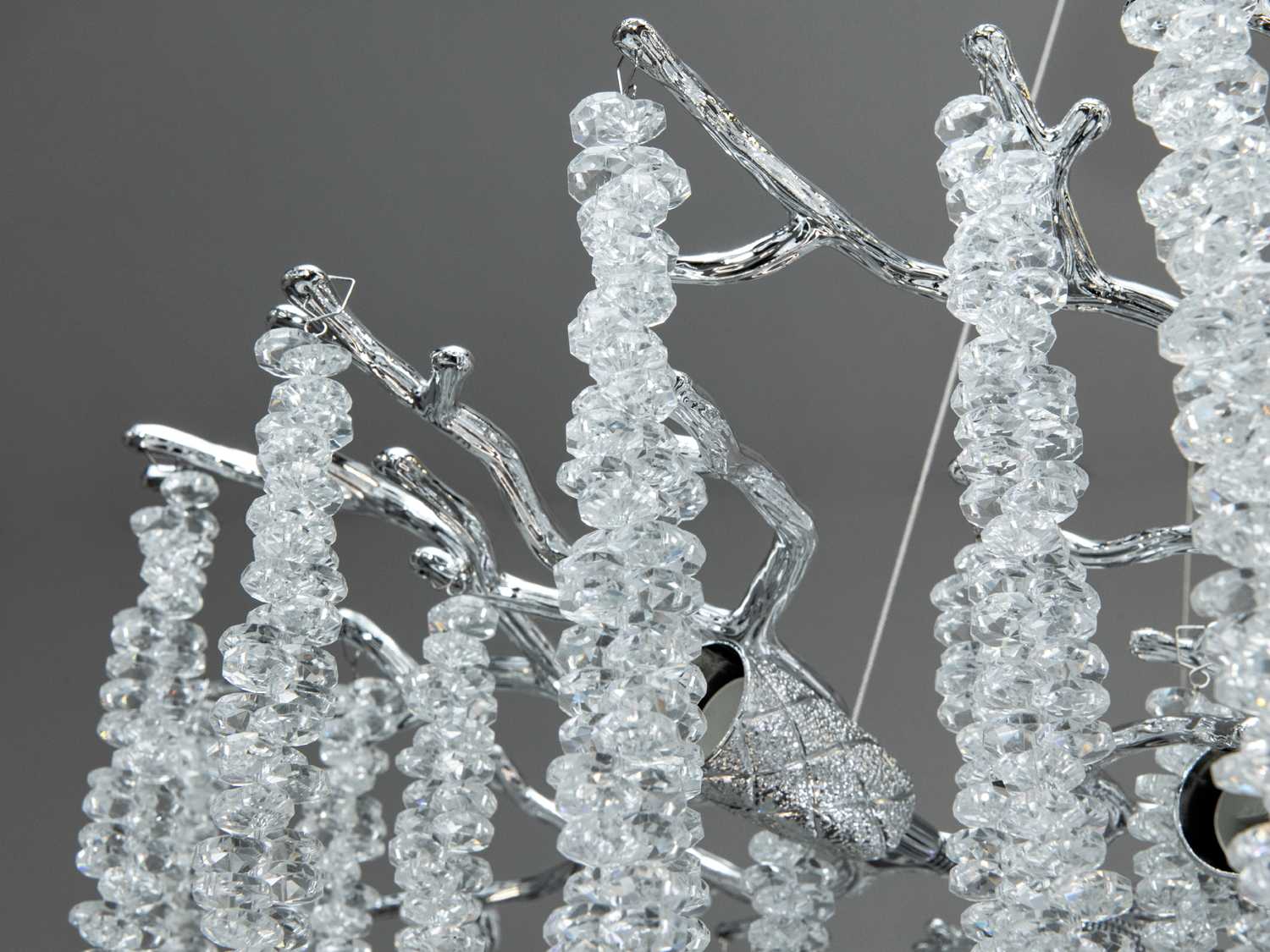 Деталь кришталевої люстри з блискучими гілками та підвісками. Витончений дизайн додає елегантності будь-якому простору.