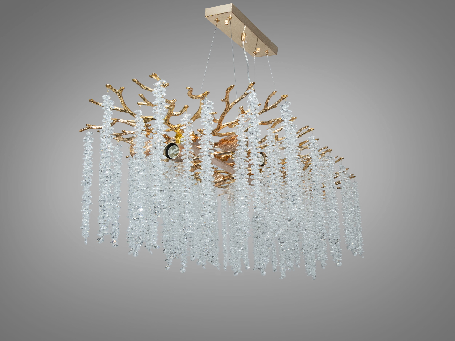 Люстра з кришталевими підвісками на золотих гілках, підвішена на прямокутній основі. Створює ефект розкішного інтер′єру.