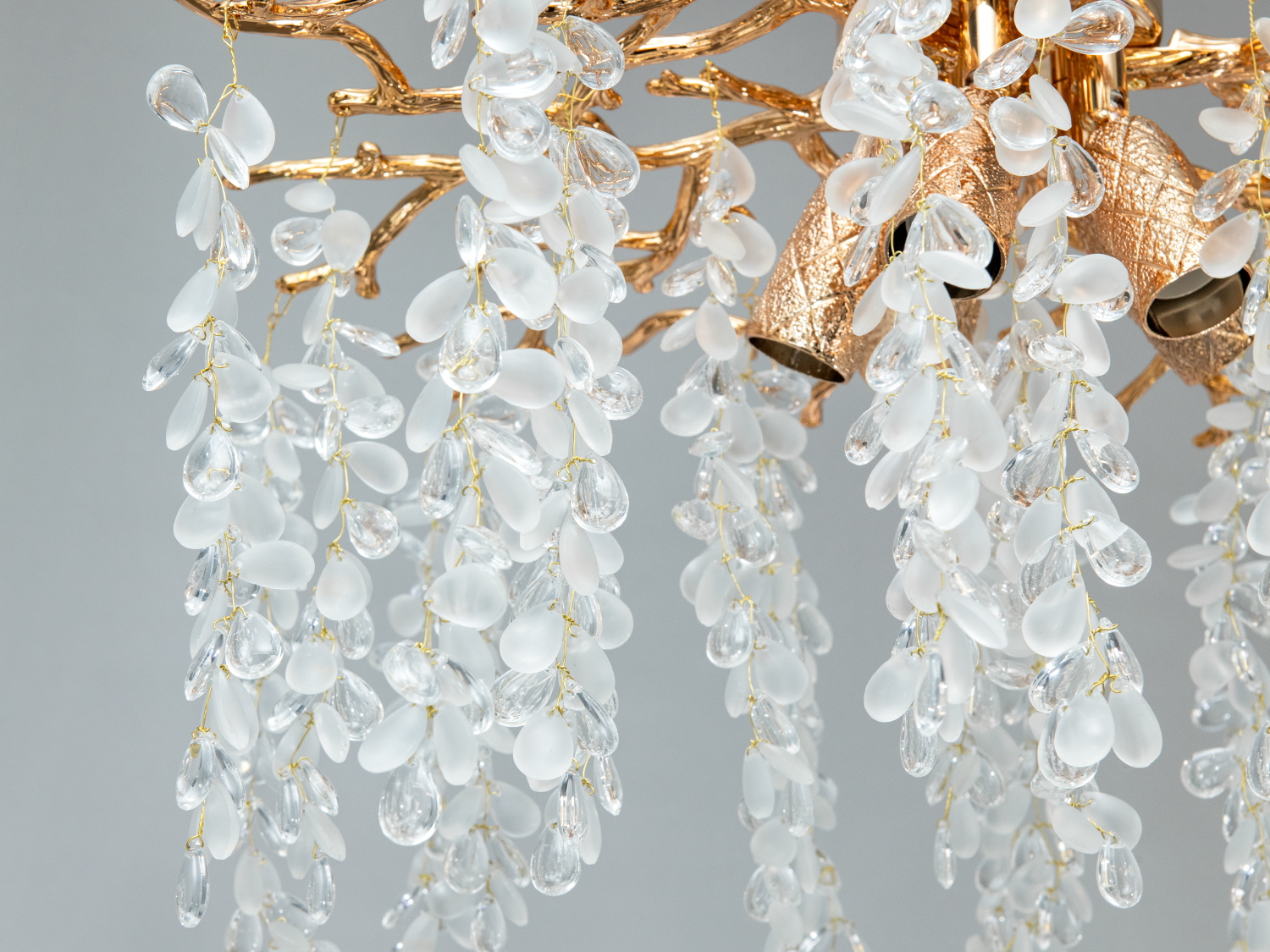 Детальний вигляд люстри з золотими гілками та кришталевими підвісками у формі крапель. Використовує кілька джерел світла.