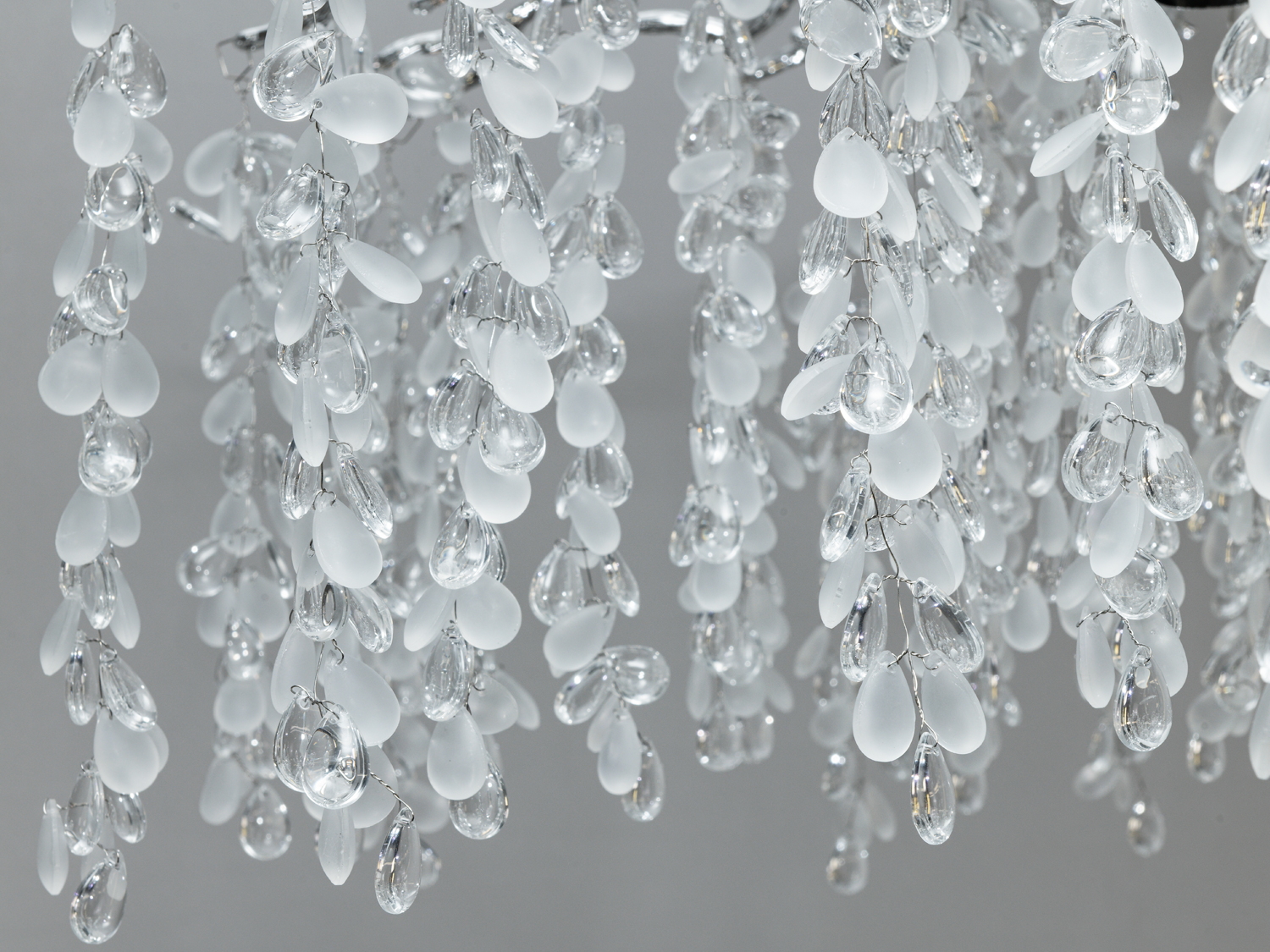 Деталь кришталевої люстри з прозорими і матовими підвісками. Відмінно підходить для створення елегантної атмосфери.