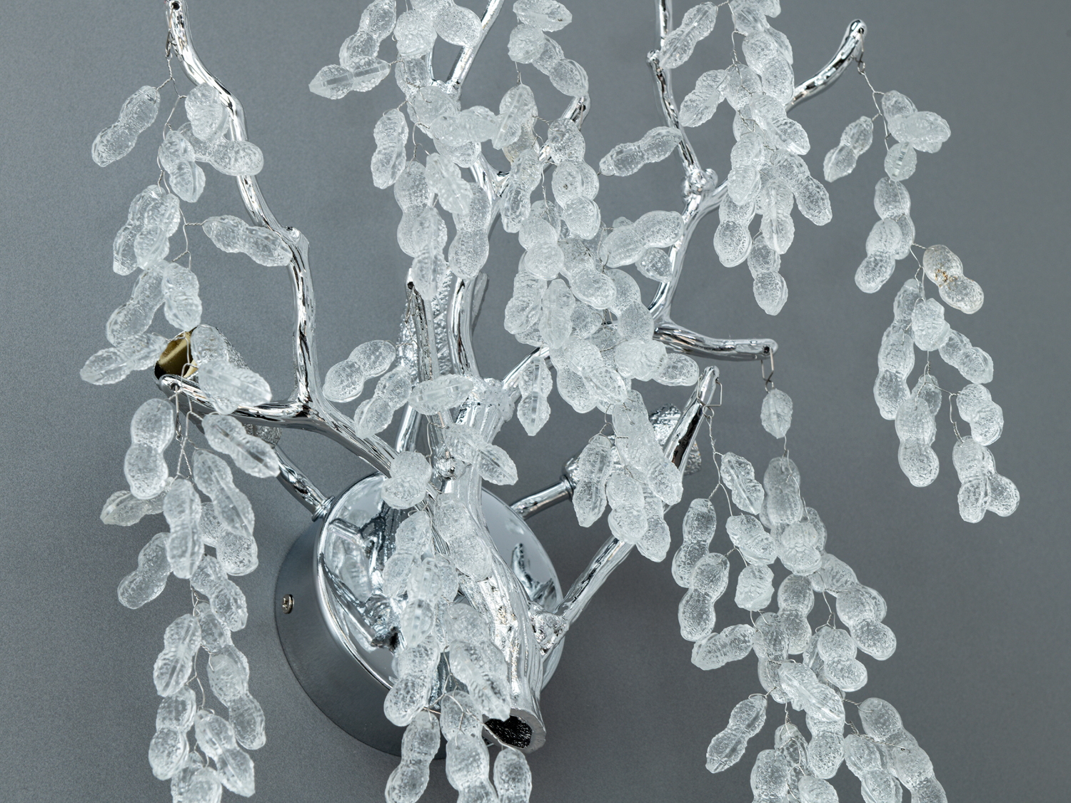 Близький план світильника з деталями кришталевих підвісок на металевій основі. Призначений для настінного монтажу.