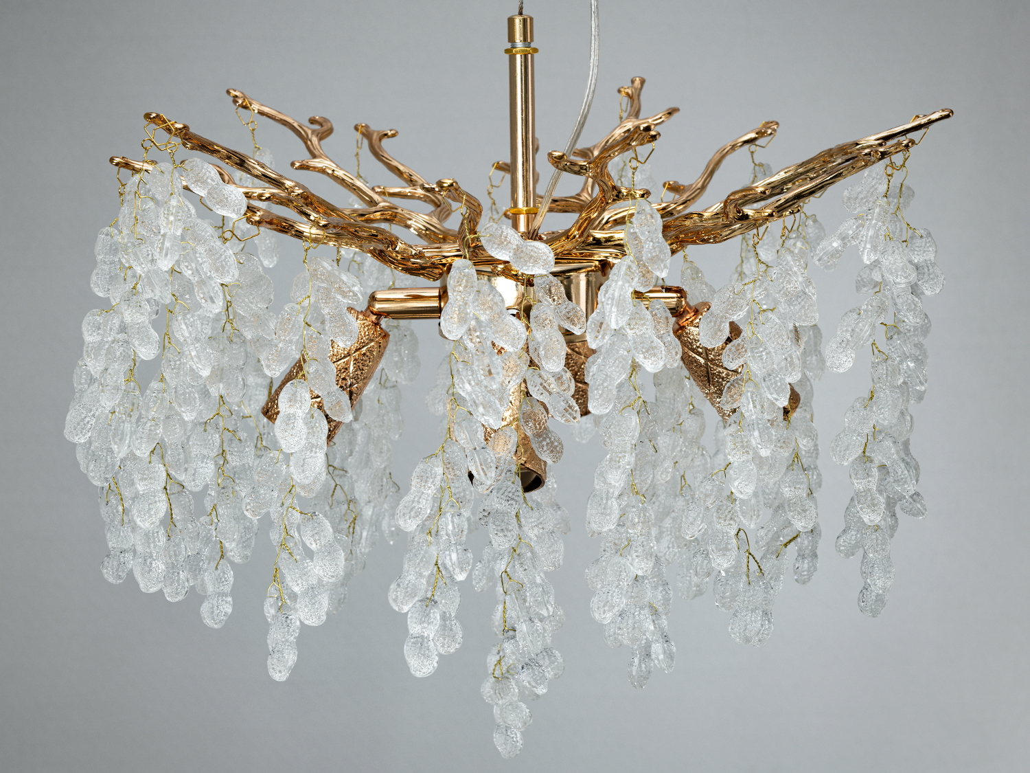 Люстра з центральною стійкою, прикрашена золотими гілками та прозорими підвісками. Підходить для класичних інтер′єрів.