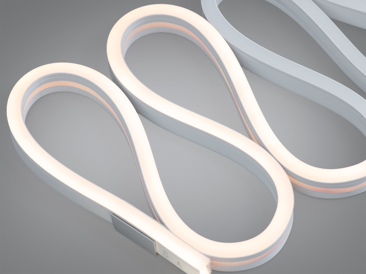 Кінець світлодіодної стрічки з видимими літерами на білій поверхні. Призначена для монтажу в різноманітних інтер′єрах.