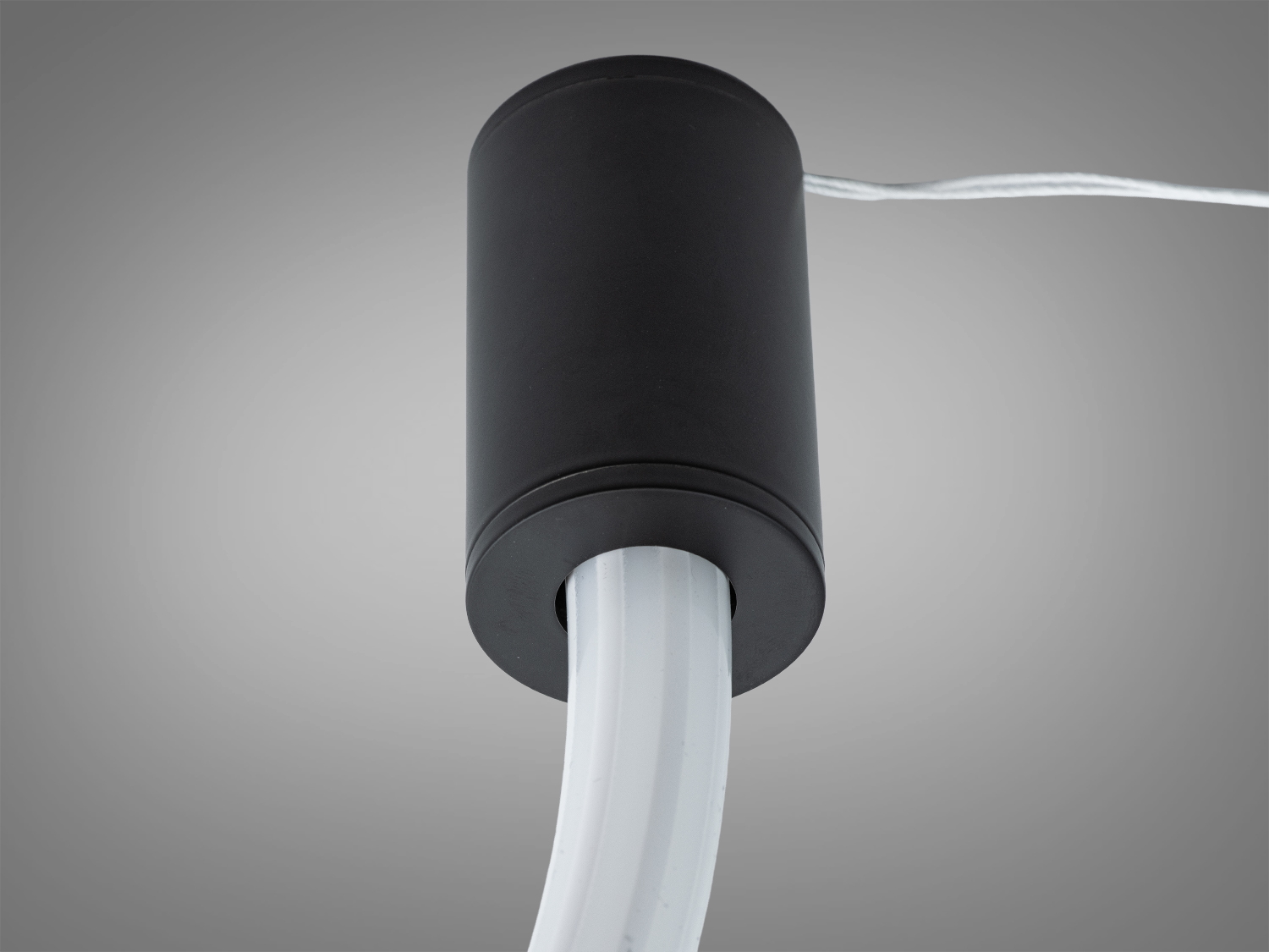 Світильник з чорним циліндричним корпусом, підключений до білого кабелю, підходить для підвісного монтажу.