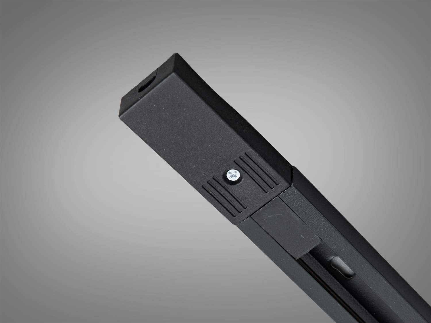 Кінцева частина чорного трекового профілю з кріпильним гвинтом, призначена для зручного монтажу в різних приміщеннях.