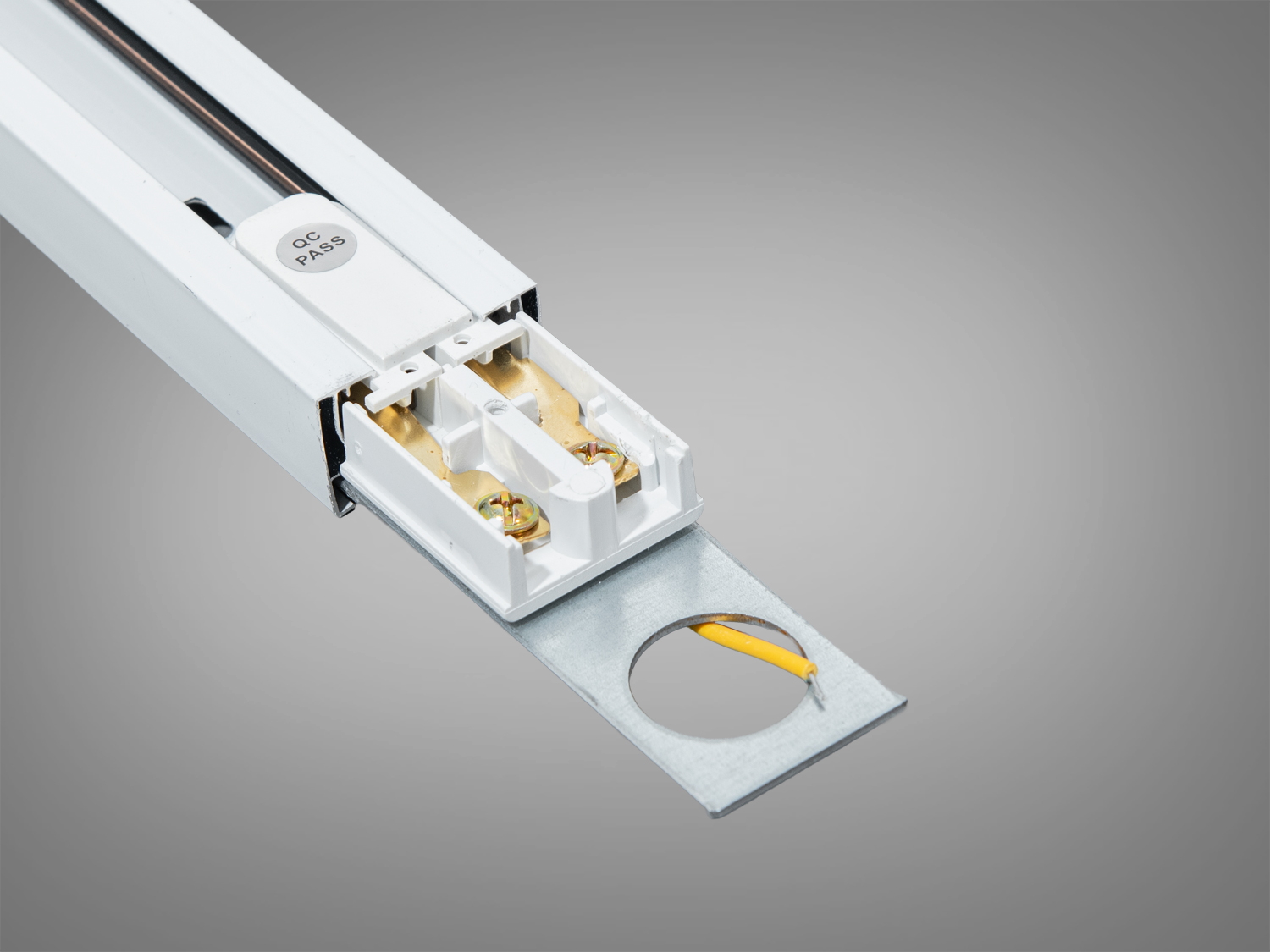 Трековий світильник з білим корпусом і металевим кріпленням. Включає електричні контакти та отвір для монтажу.