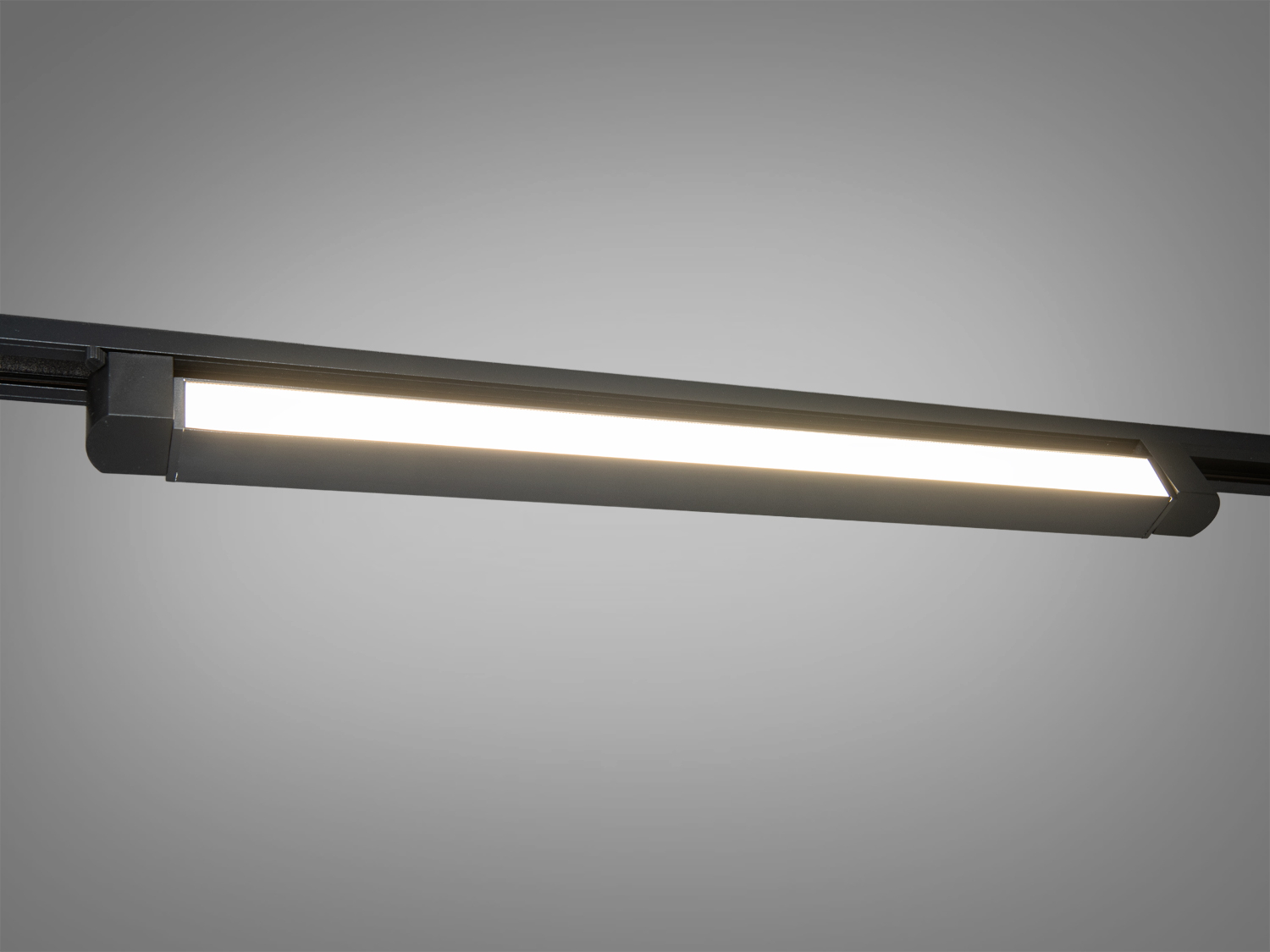 Світлодіодний світильник з прямокутним корпусом для трекового монтажу, випромінює м′яке біле світло, підходить для офісного інтер′єру.