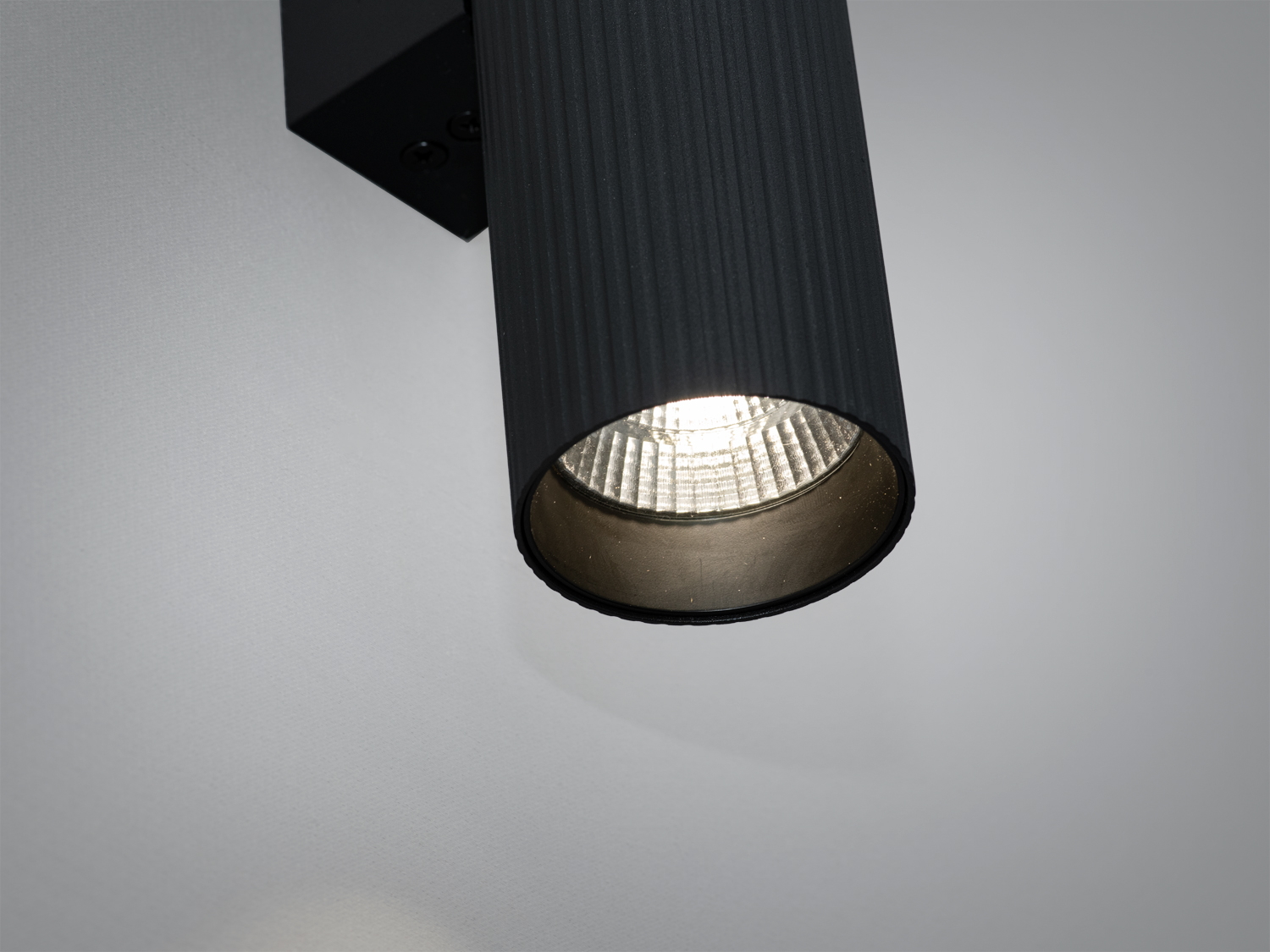 Світильник із чорного металу, циліндрична форма, з акцентом на внутрішню частину, яка відбиває світло, підходить для акцентного освітлення.
