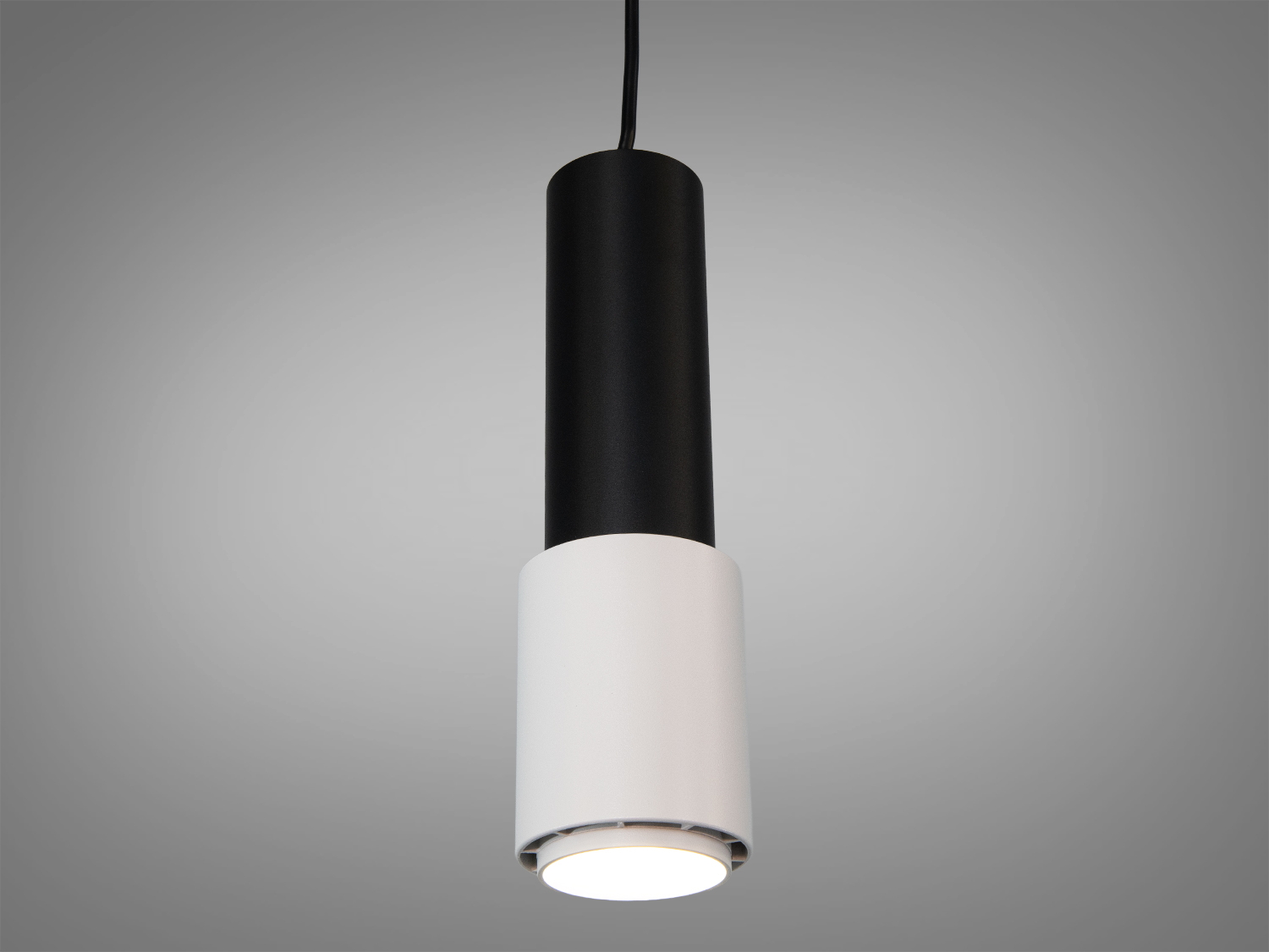 Підвісний світильник циліндричної форми з чорним корпусом і білим дифузором, підходить для сучасних інтер′єрів, забезпечує спрямоване освітлення.