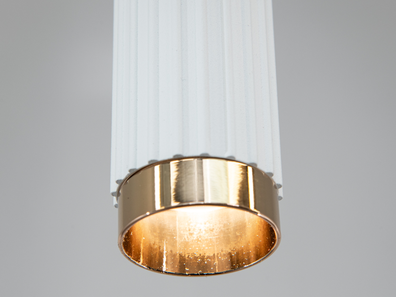 Деталь нижньої частини підвісного світильника з золотистим обрамленням, що додає елегантності.