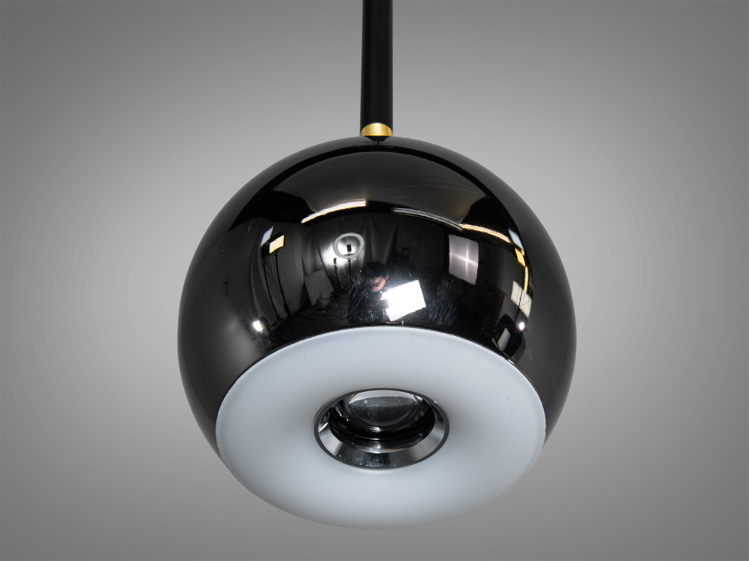 Вид знизу на підвісний світильник з чорним глянцевим плафоном і матовим білим розсіювачем для рівномірного освітлення.