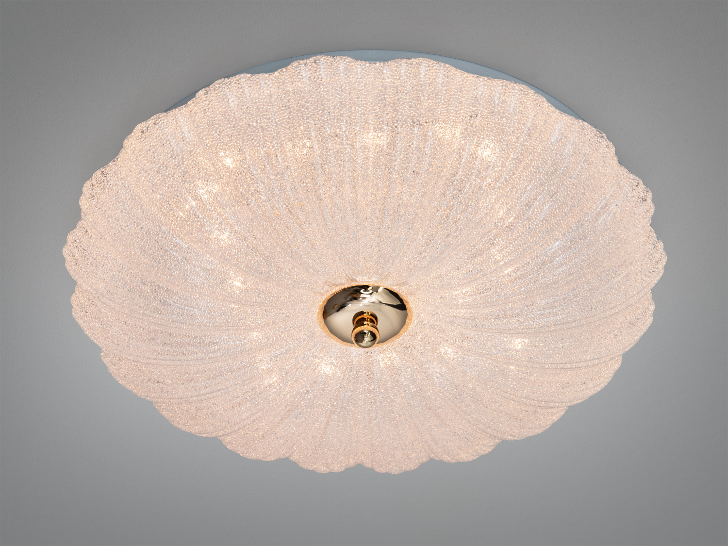 Круглий стельовий світильник з текстурованого скла, що нагадує мушлю, з центральною металевою деталлю. Ідеально підходить для сучасних інтер′єрів.