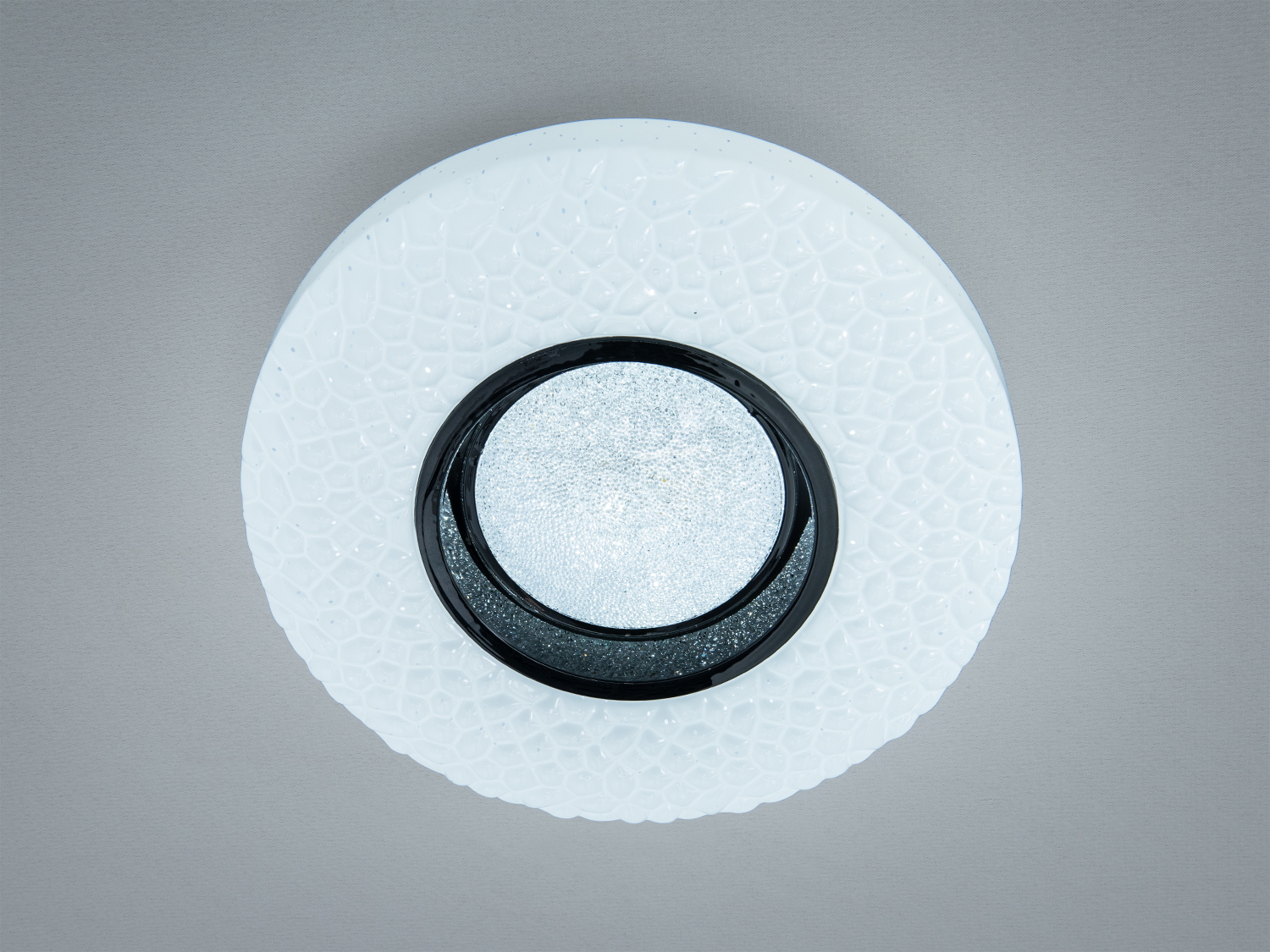 Світильник круглої форми з текстурованою поверхнею, білий колір, центральна частина чорна. Підходить для стельового монтажу.