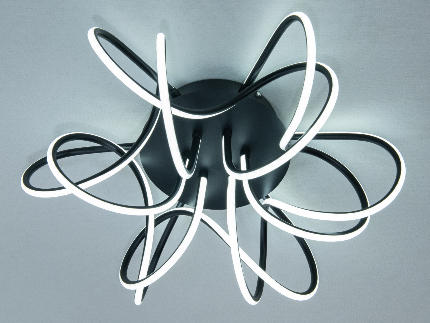 Стельовий LED-світильник з чорними металевими дугами та холодним білим світлом, що надає інтер′єру футуристичний вигляд.