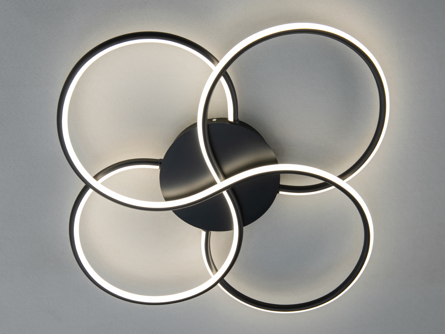 Світильник з чорним корпусом та чотирма світлодіодними кільцями, що забезпечують рівномірне освітлення. Підходить для монтажу на стелю.