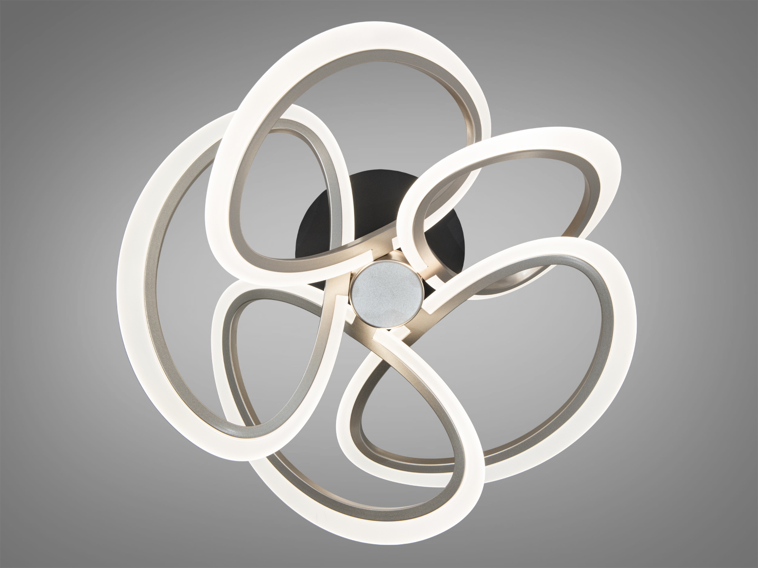 Декоративний світильник з кільцями, що утворюють плавні вигини, з теплим світлом. Підходить для вітальні або спальні.