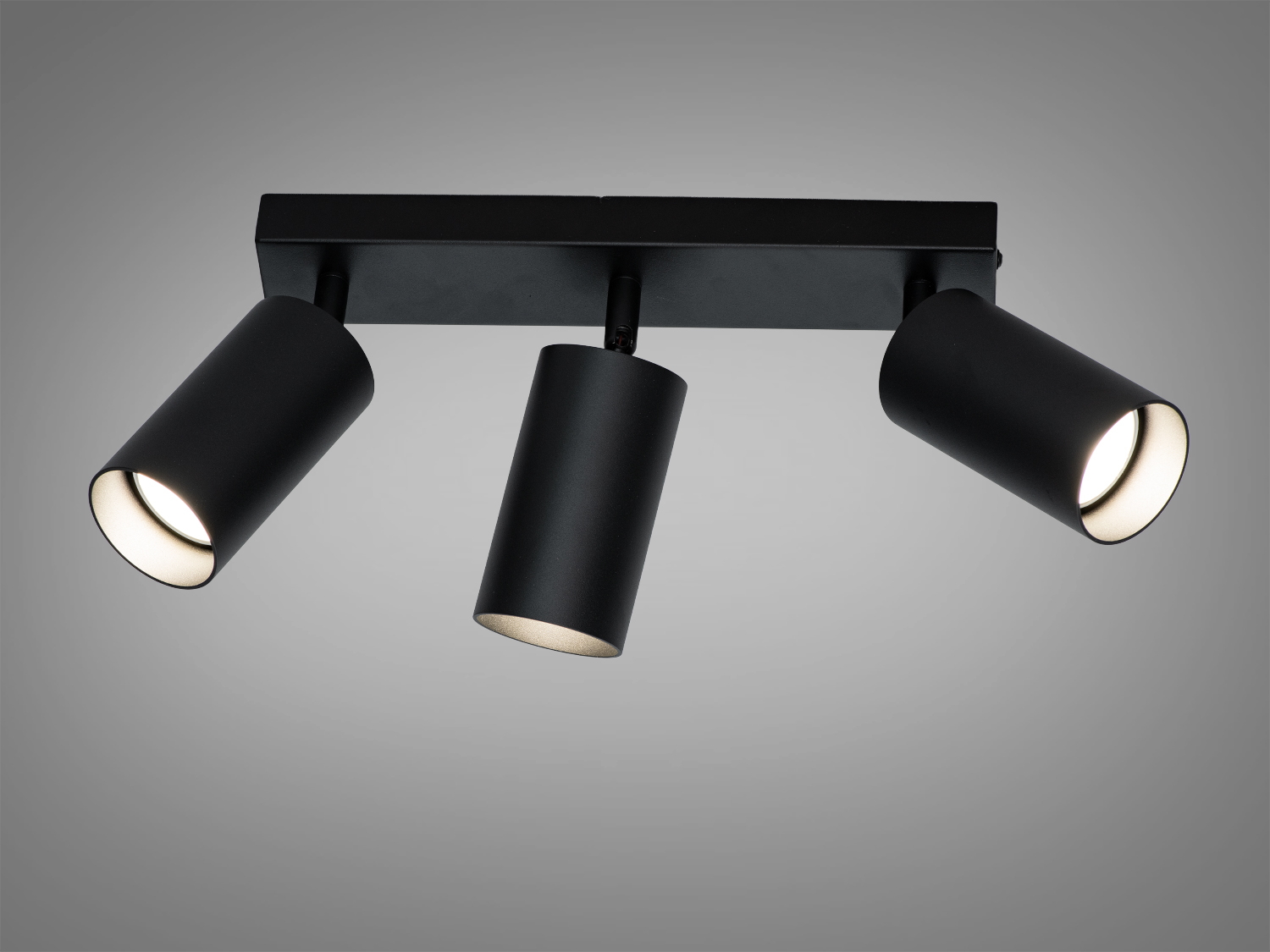 Три чорні циліндричні світильники на прямокутній основі, призначені для стельового монтажу, з можливістю регулювання напрямку світла.